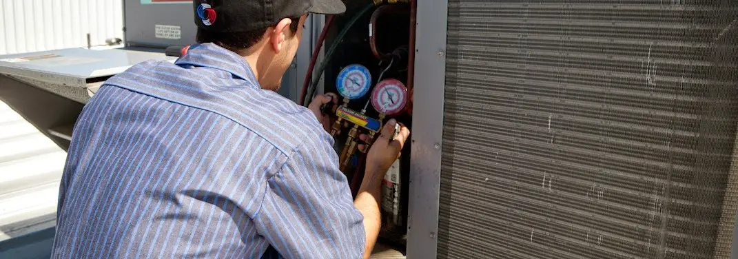 HVAC technician servicing a condenser unit in Upper