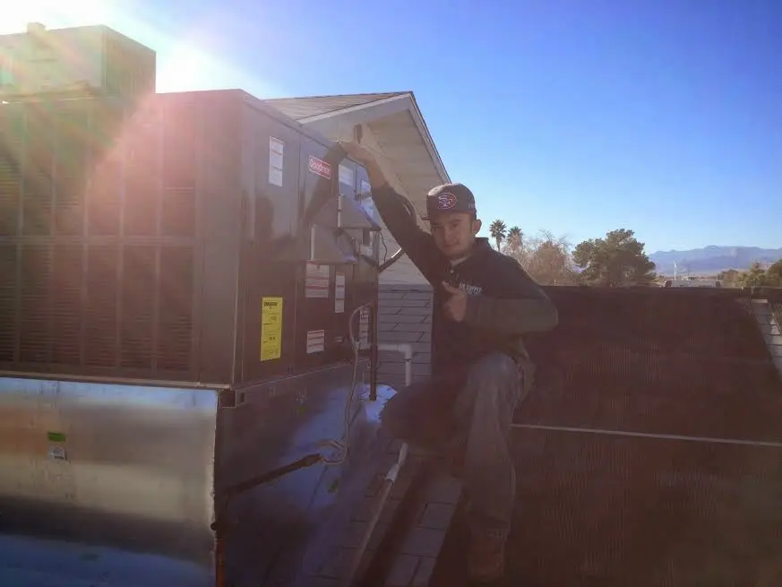 HVAC technician performing Boiler Repair on a rooftop unit in Upper